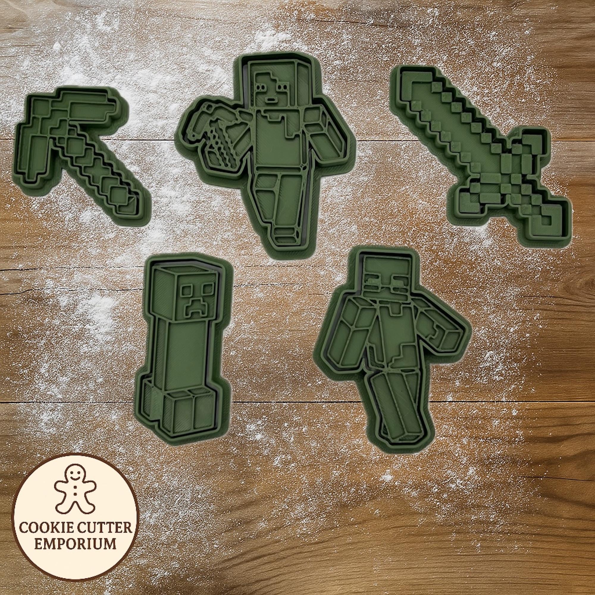 Set of green cookie cutters shaped like video game characters on a wooden surface with a rolling pin and checkered cloth.