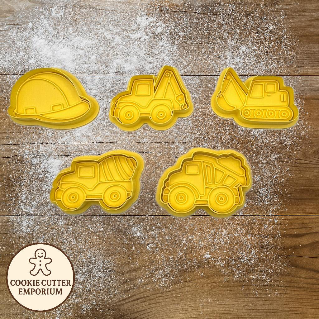 Set of yellow construction-themed cookie cutters on a wooden surface with a rolling pin and checkered towel.