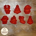Set of red cookie cutters on a wooden surface with a rolling pin and checkered towel.