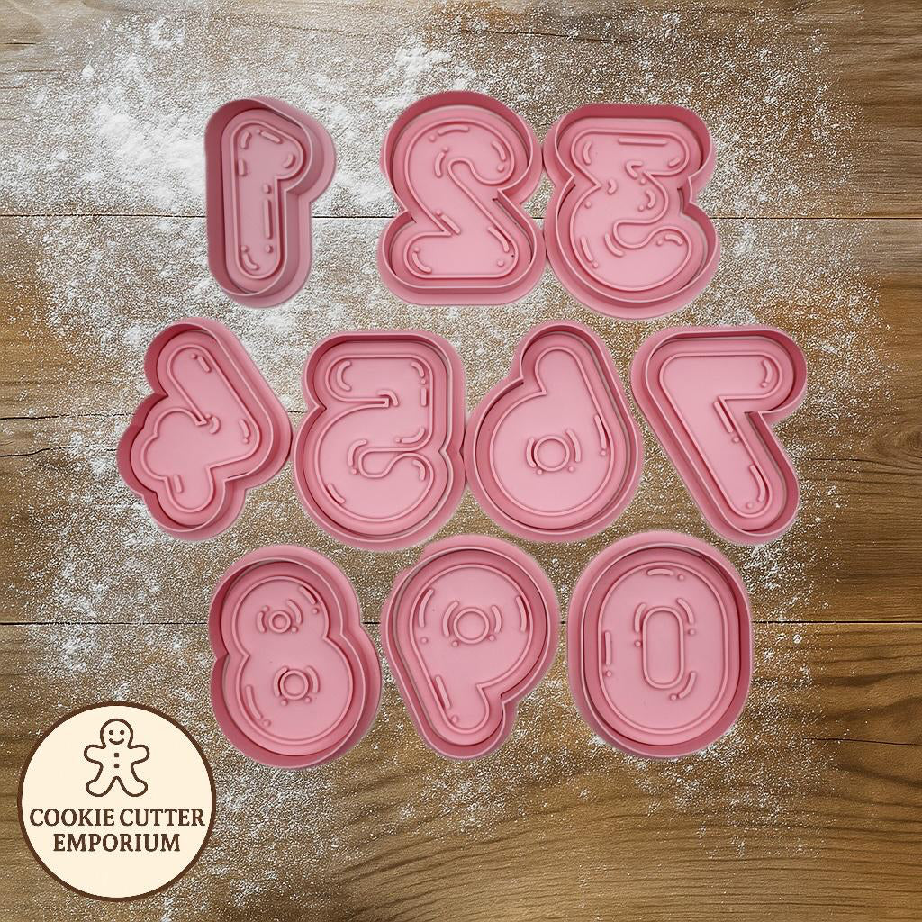 Set of pink cookie cutters on a wooden surface with a rolling pin and checkered cloth.